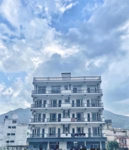 un edificio blanco alto con un cielo nublado en el fondo en HOT - House Of Travellers en Rishīkesh