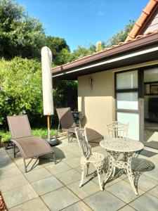 Zimbali 1Bedroom Self - catering Apartment في باليتو: فناء مع طاولة وكراسي ومظلة