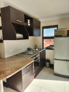 Zimbali 1Bedroom Self - catering Apartment في باليتو: مطبخ بخزائن خشبية وثلاجة بيضاء