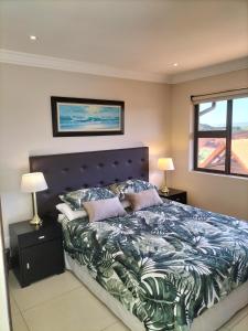 Zimbali 1Bedroom Self - catering Apartment في باليتو: غرفة نوم بسرير كبير عليها مخدات