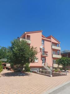 un edificio rosa con un árbol delante de él en Apartments Marta en Seline