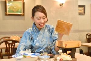 a woman sitting at a table eating food at Hotel Seawave Beppu in Beppu