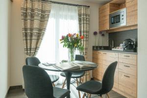 einen Tisch mit Stühlen und eine Vase Blumen in der Küche in der Unterkunft Hotel La Romantica in Le Prese, Poschiavo
