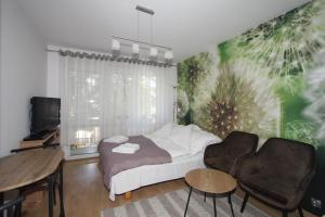 a bedroom with a bed and two chairs and a tv at Nadmorskie Pokoje i Apartamenty in Krynica Morska