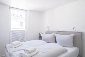 białe łóżko z 3 ręcznikami na górze w obiekcie JOHOUSE Apartment 14 w mieście Warnemünde