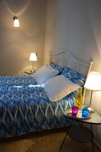 a bed with a blue comforter and two tables with lamps at B&B Le Coppole in Palermo