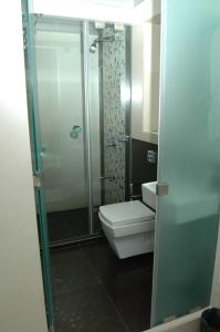 a bathroom with a toilet and a glass shower at Hotel Causeway, Colaba in Mumbai