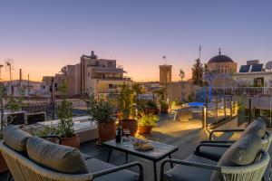 a balcony with chairs and tables on a building at Meno Suite with Private Terrace - Jaccuzzi, Acropolis View in Athens