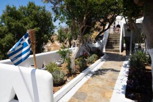 una casa con bandera griega en un jardín en Zisis Pension en Agios Stefanos