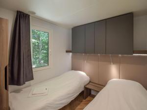 two beds in a small room with a window at Cottage on the edge of the fishing pond in Laurière