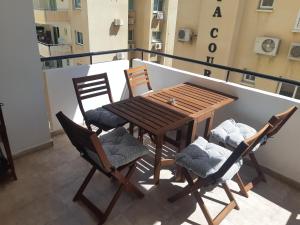 een houten tafel en stoelen op een balkon bij Beautiful apartment near beach in Larnaca in Scala