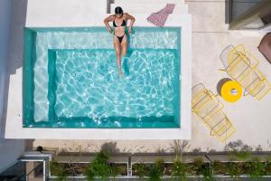a woman in a swimsuit jumping into a swimming pool at Alkima Athens Hotel in Athens