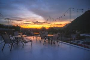 a group of tables and chairs on a balcony with a sunset at Art by Yui House in Ban Tha Maprang
