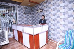 een vrouw staat achter een toonbank in een kamer met tegels bij Canari Hotel kashmir view in Nathia Gali