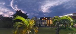 a large building with palm trees in front of it at Hotel Mechi Crown in Kakarvitta