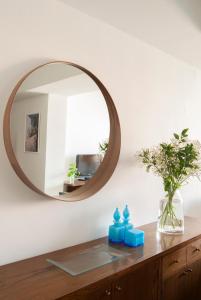 um espelho numa parede por cima de uma cómoda de madeira com velas azuis em Apartment near the beach and Port Marina of Premia em Premiá de Mar