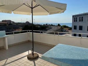 a balcony with an umbrella and a mattress at BREZZA DI MARE - attico vista mare con terrazza in Termoli