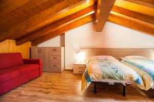 1 dormitorio con 1 cama y 1 sofá rojo en Albergo Diffuso Dolomiti en Forni di Sotto