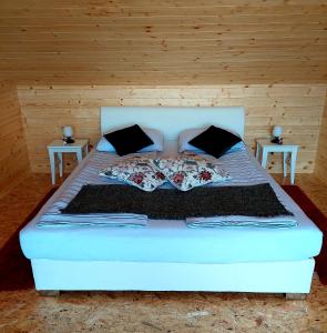 a bedroom with a white bed with two tables at HERBALIJA Apartment Herbalija - sorrounded by Nature in Podčetrtek