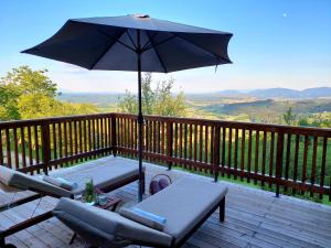 a patio with an umbrella and chairs on a deck at HERBALIJA Apartment Herbalija - sorrounded by Nature in Podčetrtek