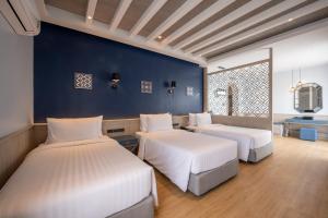 een slaapkamer met 2 bedden en een blauwe muur bij Seabed Grand Hotel Phuket - SHA Extra Plus in Phuket