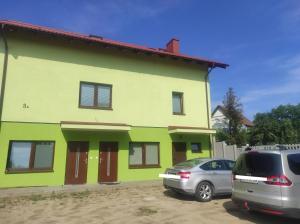 een geel en groen huis met twee auto's aan de voorkant bij Nocleg na Poziomkowej in Kościerzyna