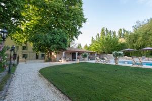 a yard with a pool and chairs and a house at La Bastide des Lavandins in Le Thor