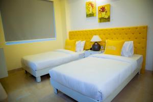 two beds in a hotel room with yellow pillows at Luxury Studio Service Apartment Lime Tree -Near Artemis Hospital, Gurgaon Sector - 51 in Gurgaon