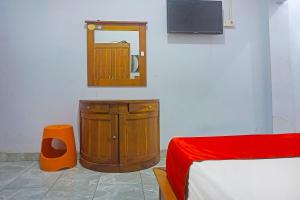 a room with a dresser and a mirror and a bed at OYO 91456 Anggrek Homes Makassar in Makassar