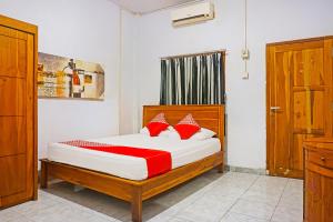 een slaapkamer met een bed met rode kussens bij OYO 91456 Anggrek Homes Makassar in Makassar