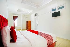 a bedroom with a red and white bed and a television at OYO 91460 Guest House Kencana Syariah in Bandar Lampung