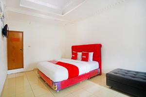 a bedroom with a red and white bed and a couch at OYO 91460 Guest House Kencana Syariah in Bandar Lampung