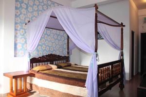 a bedroom with a canopy bed and a table at Solomon Beach Hotel in Marawila