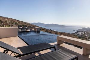 a pool with chairs and a view of the ocean at Nimbus Santorini in Oia