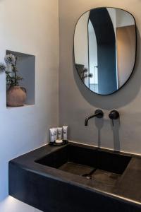 baño con lavabo negro y espejo en Nimbus Santorini, en Oia 37 fotos más