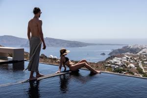 a man and a woman sitting on a board in the water at Nimbus Santorini in Oia
