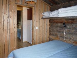 a bedroom with a bed and a wooden wall at Karhujärven Kelopirtit in Karhujarvi