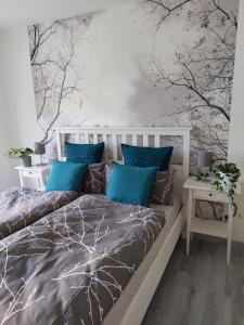 Schlafzimmer mit einem Bett mit blauen Kissen und Bäumen an der Wand in der Unterkunft Gemütliches, voll ausgestattetes Apartment in Halle an der Saale