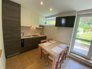 cocina con mesa de madera con sillas y fregadero en Apartment Pusynas en Nida