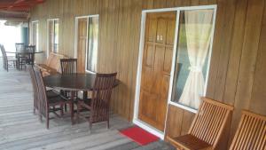 porche de madera con mesa y sillas en la cubierta en New Cottage Asri Karimunjawa, en Karimunjawa
