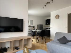 Una sala de estar con un televisor de pantalla plana grande en una pared. en Appartement familial, à Chessy, la ville de Disneyland Paris, en Chessy