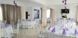 a banquet hall with white tables and purple chairs at Pensiunea Magnolia din Tismana in Tismana