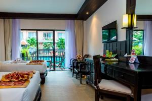 a hotel room with two beds and a desk and a balcony at Nipa Resort, Patong Beach - SHA Extra Plus in Patong Beach