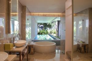a bathroom with two sinks and a bath tub at Maya Sanur Resort & Spa in Sanur