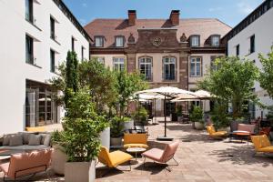 斯特拉斯堡Hôtel LÉONOR the place to live的建筑前方的庭院配有桌椅