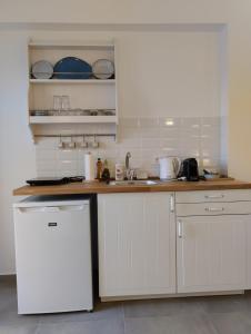 a kitchen with white cabinets and a white refrigerator at Κallisto rooms in Mytakas