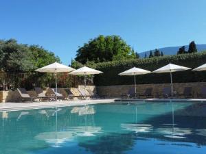 a swimming pool with chairs and umbrellas at Mas des Olives in Bédoin