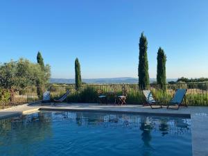 a swimming pool with chairs and a table and trees at Mas des Olives in Bédoin