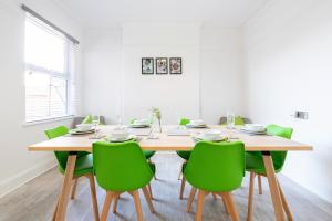 une salle à manger avec une table en bois et des chaises vertes dans l'établissement Jasmine Villa B - Ideal for QMC & Uni - Free parking, à Nottingham