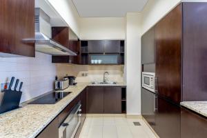 a large kitchen with wooden cabinets and a sink at Maison Privee - Luxury 1BR Apt Few Steps Away from the Beach in Dubai